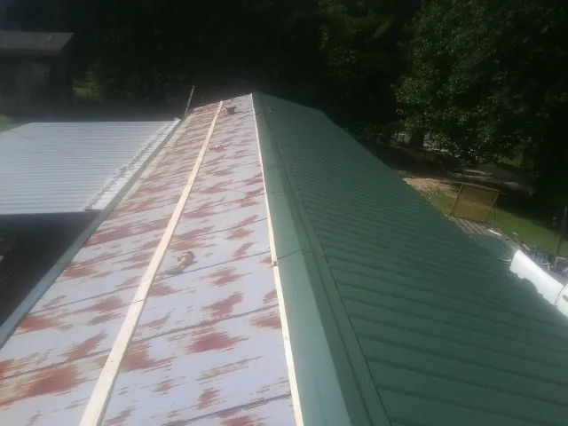 Old rusted panels beside newly installed green metal roofing — Wind Damage Roof Repair by Roofing Brothers in Shawsville