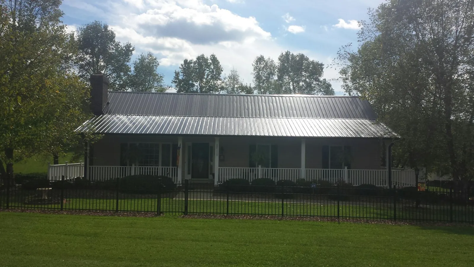 Gray metal roof on a brick ranch with a full width front porch — Gutter Guard Installation work by our crew in Shawsville