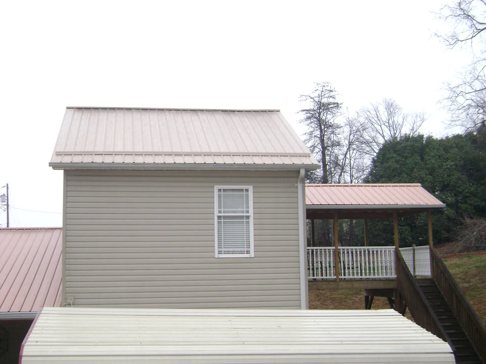 Tan metal roofs on a two story addition and attached porch, from a Roof Replacement job in Shawsville