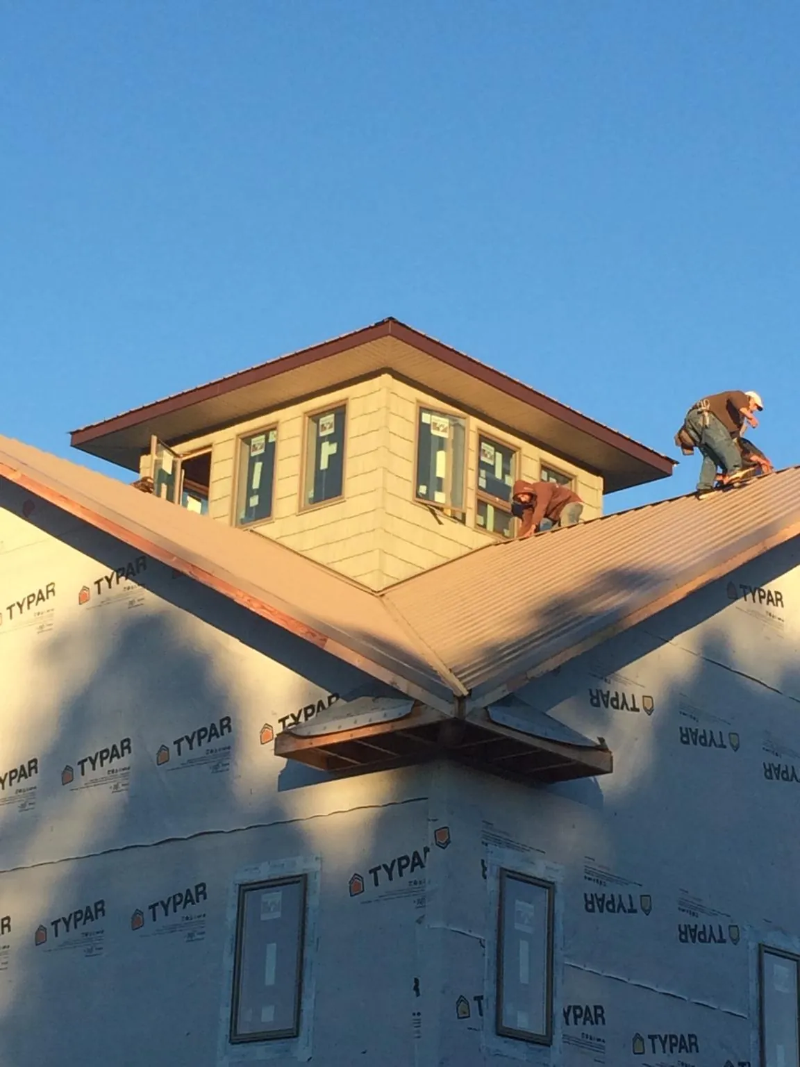 Roofers working around a rooftop cupola on a new metal roof at sunset — Roof Waterproofing in Shawsville by Roofing Brothers